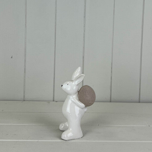 White ceramic rabbit holding an egg, spring-themed decorative figurine by Satchville.