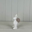 White ceramic rabbit holding an egg, spring-themed decorative figurine by Satchville.