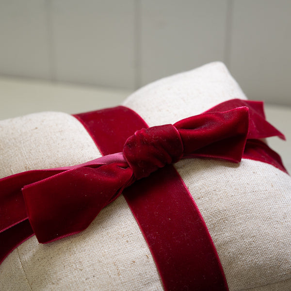 Close-up of the red velvet bow and natural linen weave on the Christmas present doorstop