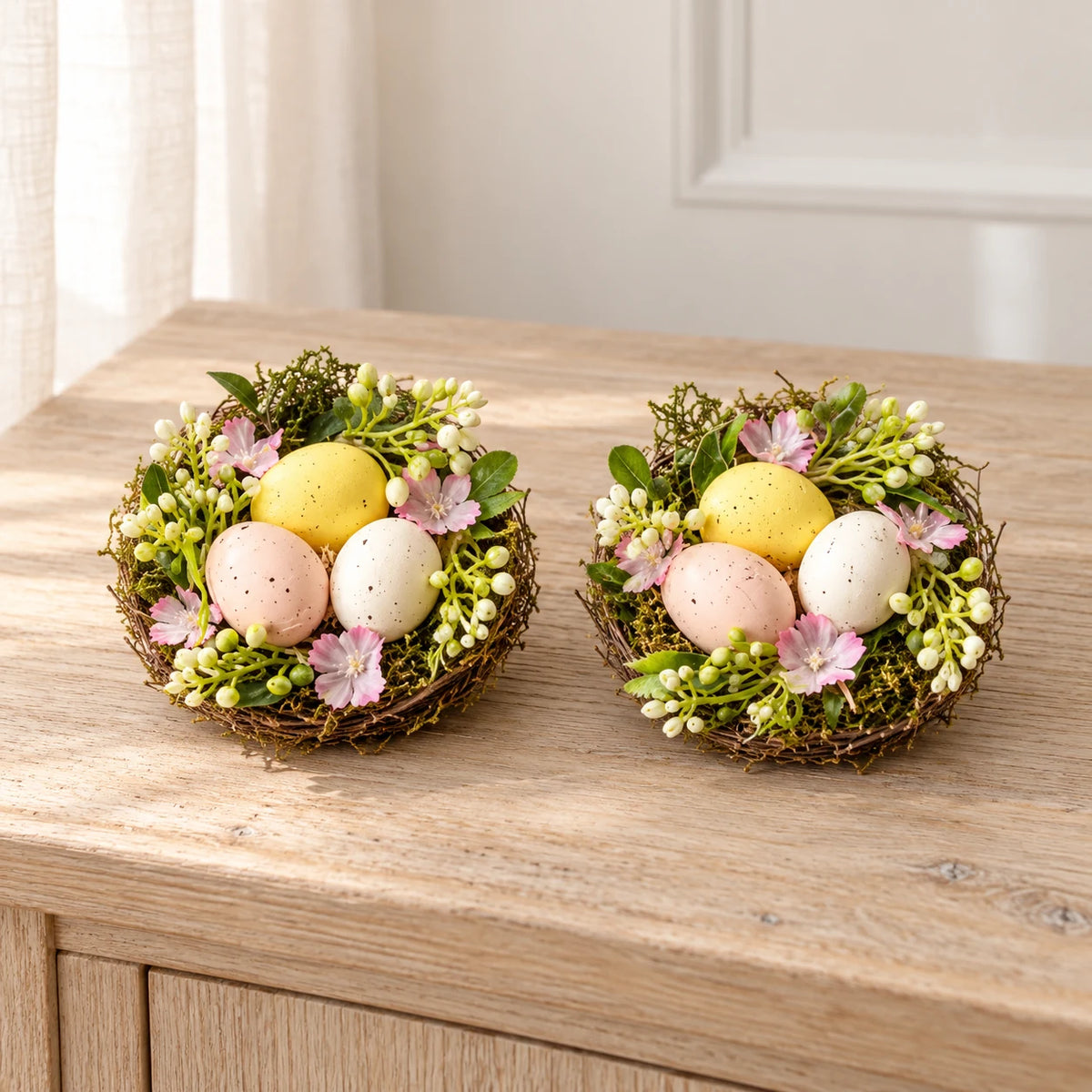 Set of two decorative pastel egg nests with pink flowers and greenery, packaging removed, hero view.