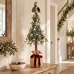Pine spruce tree with burgundy bow styled on an oak hallway console