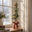 Pine spruce tree with burgundy bow on a country home window ledge