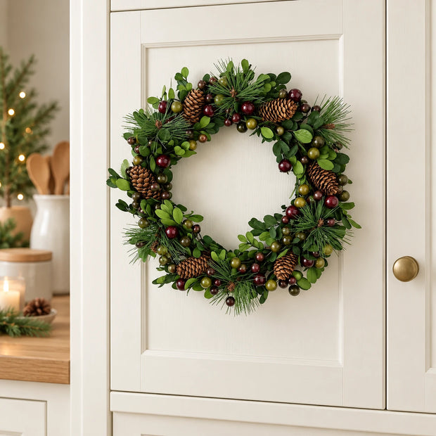 Satchville Christmas pinecone and berry wreath hanging in a kitchen for festive holiday decor.