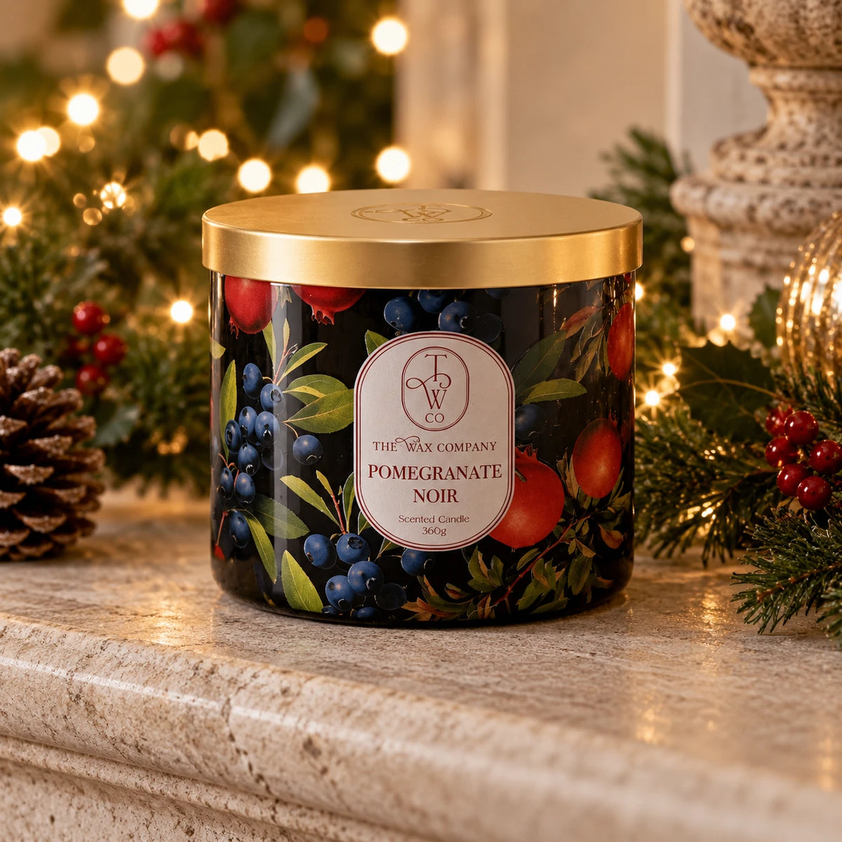 Pomegranate Noir lidded candle on a stone mantel with festive lights