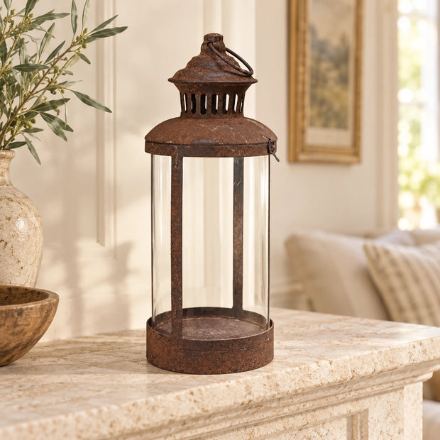 Ragna Rust Lantern — on a pale stone mantel in a bright cream country room