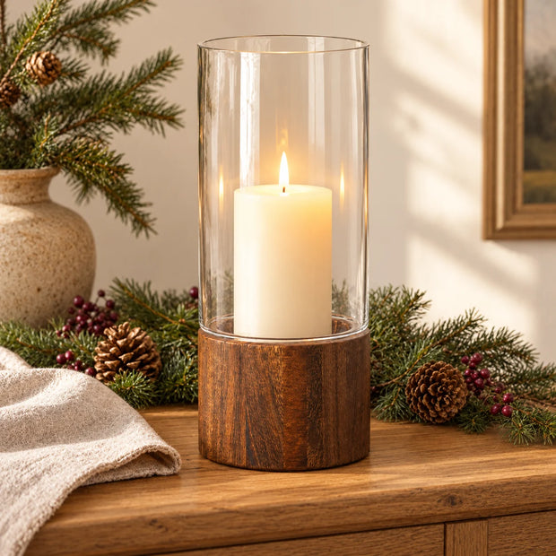 Large Raya clear glass and wood lantern with a candle, styled with spruce, pinecones and red berries on an oak sideboard