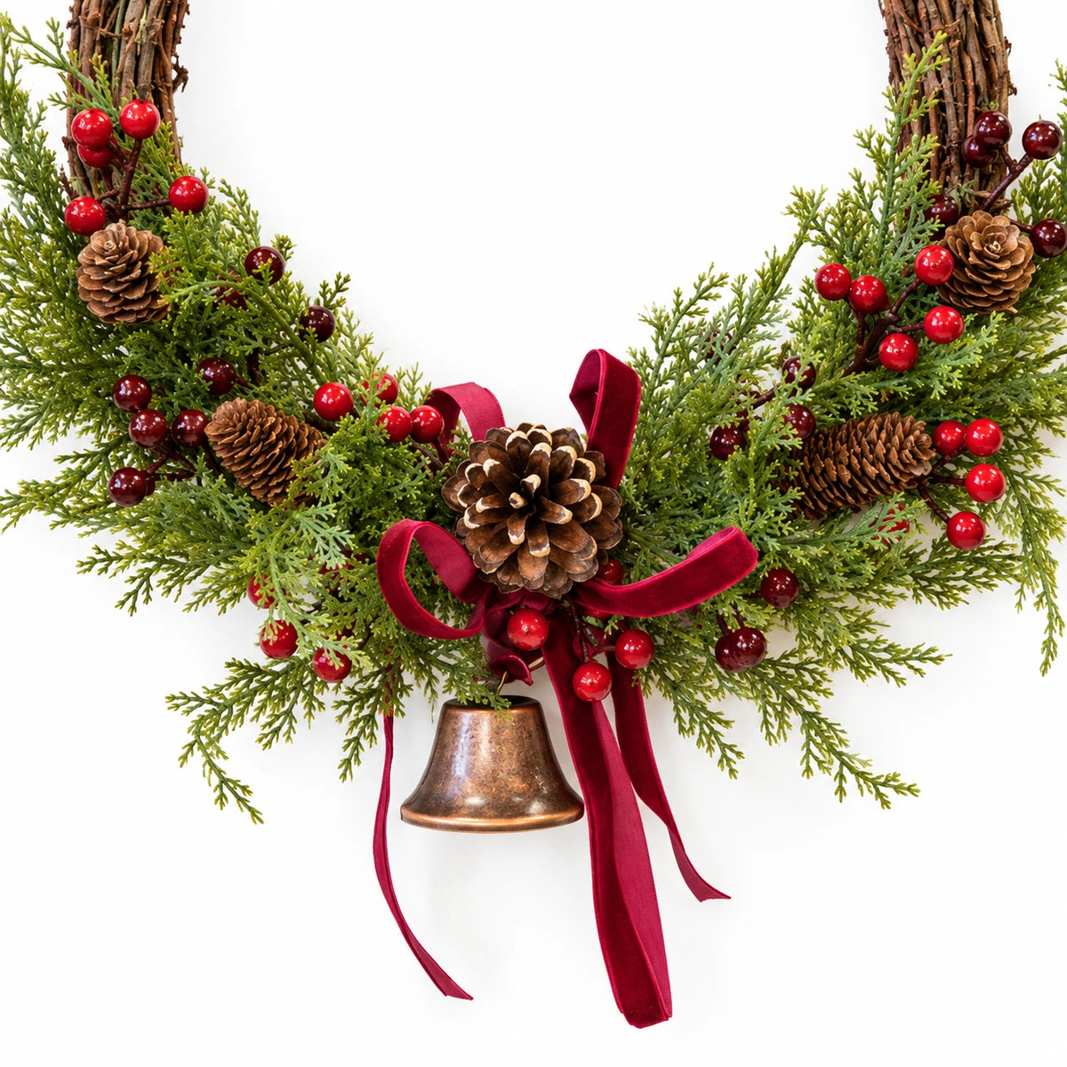 Large red berry twig Christmas wreath with pinecones, bell and bow, close-up detail