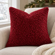 Red burgundy bouclé cushion cover on an oatmeal armchair with a cream throw