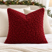 Red burgundy bouclé cushion cover styled with ivory bedding and Christmas greenery