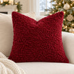 Red burgundy bouclé cushion cover styled on a cream sofa beside a Christmas tree