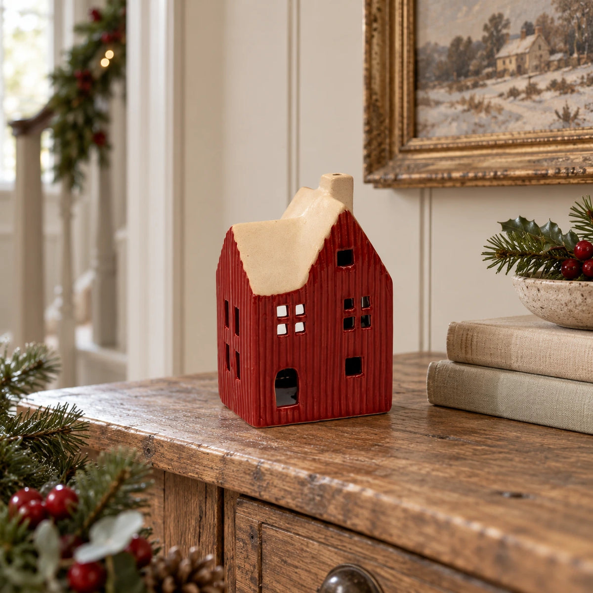 Red ceramic house tealight holder styled on an oak Christmas console