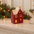 Red ceramic house tealight holder glowing on a Christmas mantel
