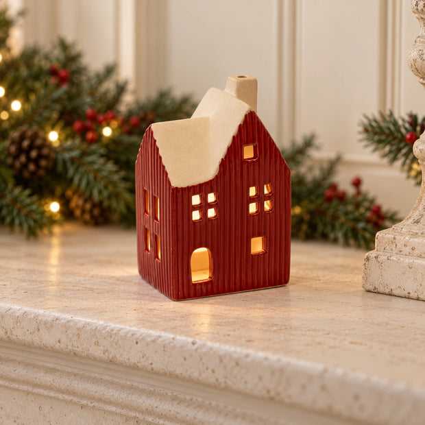 Red ceramic house tealight holder glowing on a Christmas mantel