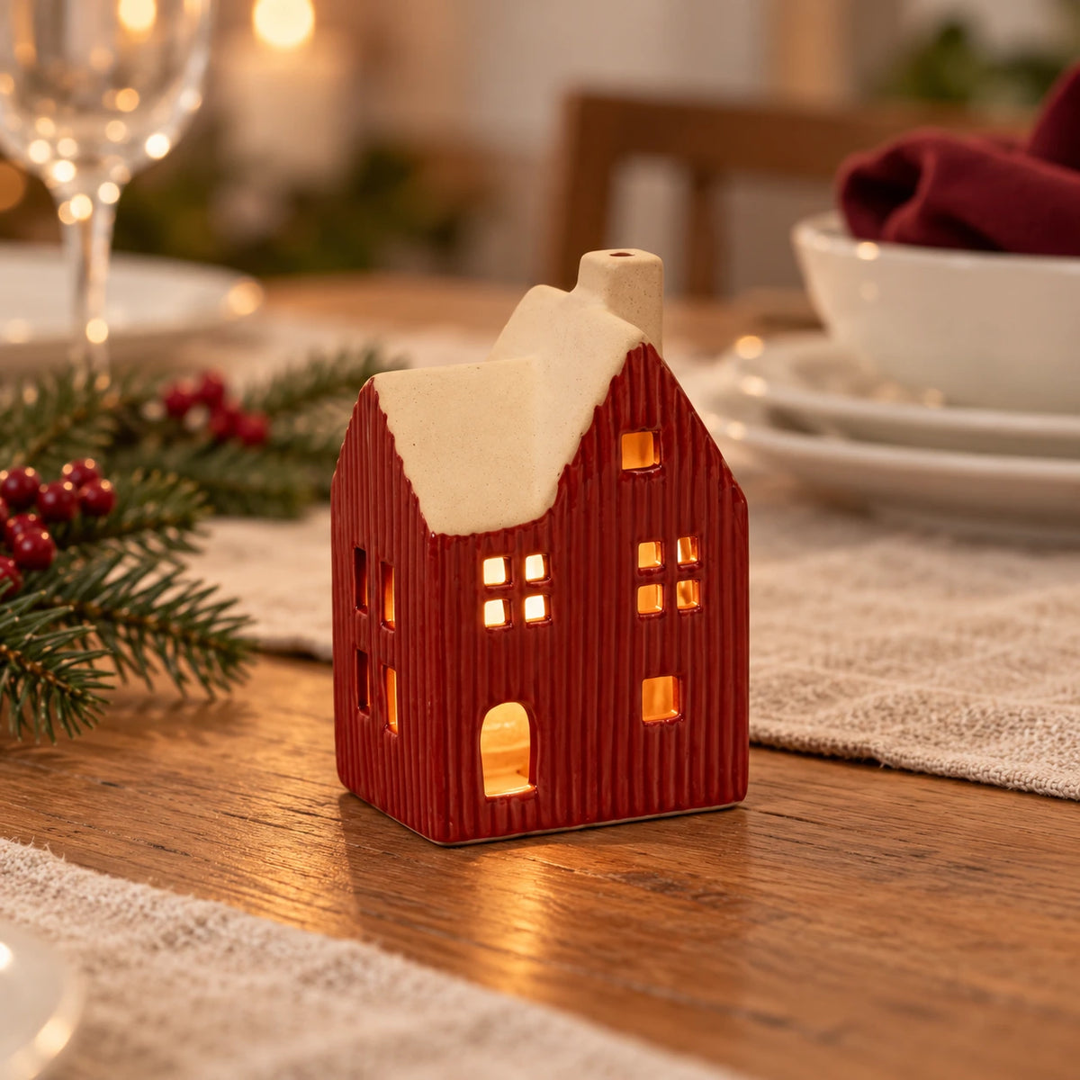 Red ceramic house tealight holder glowing on a festive dining table