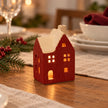 Red ceramic house tealight holder glowing on a festive dining table