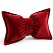 Angled studio view of the red bow cushion showing ribbed corduroy, gathered lobes and matching centre band.