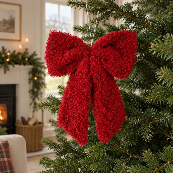 Red fluffy bow hanging for Christmas decor, styled on a white background by Heaven Sends.