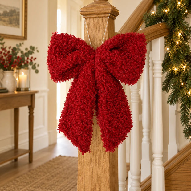 Red fluffy hanging bow on an oak stair newel.