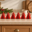 Six red paper tree ornaments on a kitchen counter with a mug of tea.