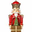 Close-up of red musical soldier crown, face, gift and small Christmas tree