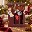 Red Christmas stockings and gold baubles surrounding a burgundy Candlelight Products Ltd candle, festive holiday decoration.