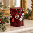 Red Christmas stockings and baubles decorated with a Burgundy Candle by Candlelight Products Ltd on a festive mantel.