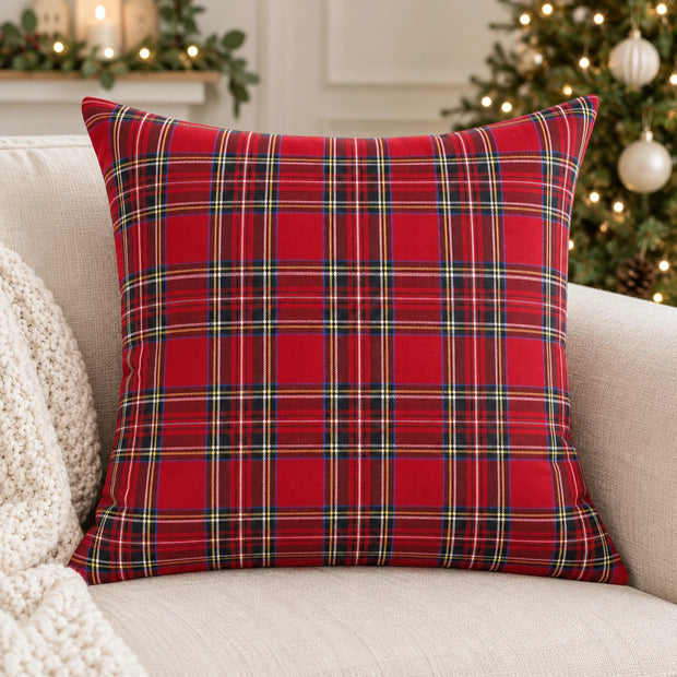 Red tartan check cushion cover on a cream sofa beside a Christmas tree with ivory baubles