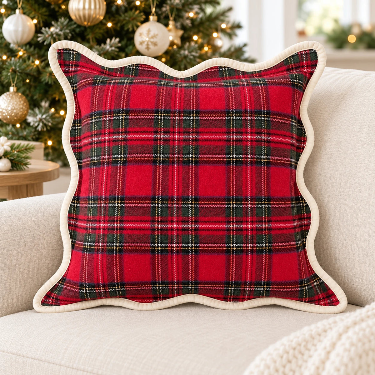 Red tartan cushion cover with cream scalloped trim on a cream sofa beside a Christmas tree
