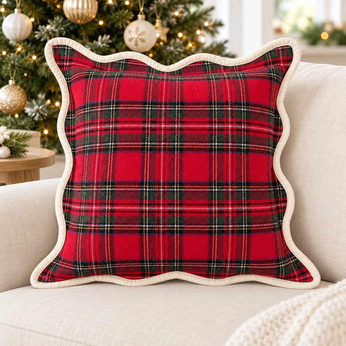 Red tartan cushion cover with cream scalloped trim on a cream sofa beside a Christmas tree