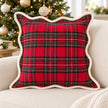 Red tartan cushion cover with cream scalloped trim on a cream sofa beside a Christmas tree