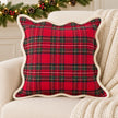Red and green tartan cushion cover on a cream armchair with festive greenery