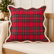 Scalloped red tartan cushion cover on an oak bench with neutral Christmas decorations