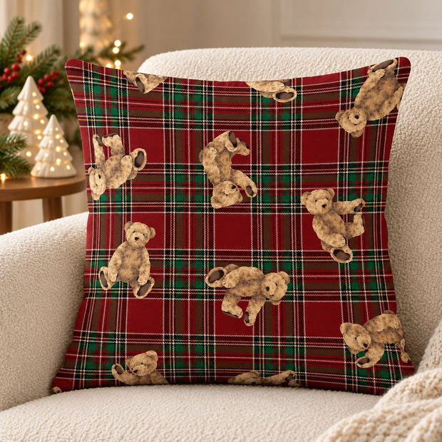Red tartan teddy bear cushion cover on a cream armchair with ceramic Christmas trees