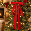 Red velvet Christmas bow with long ribbon tails among festive tree branches