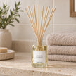 Heaven Scent RHUBARB & GINGER 100ml reed diffuser styled on a stone bathroom shelf with reeds inserted.