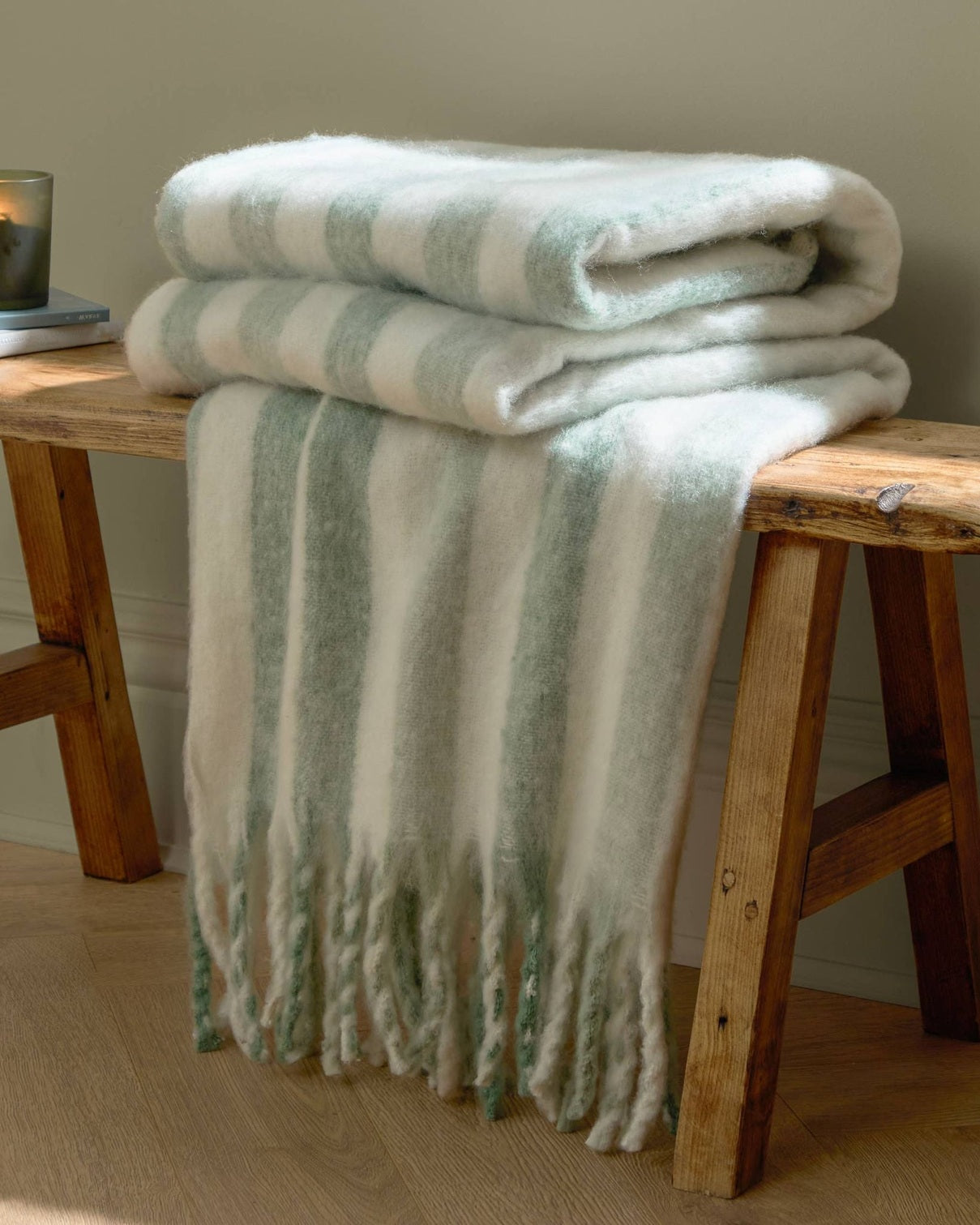 Beechwood woven stripe throw blanket in sage green from Riva Home, showcasing soft, cozy woven fabric with stripe pattern.