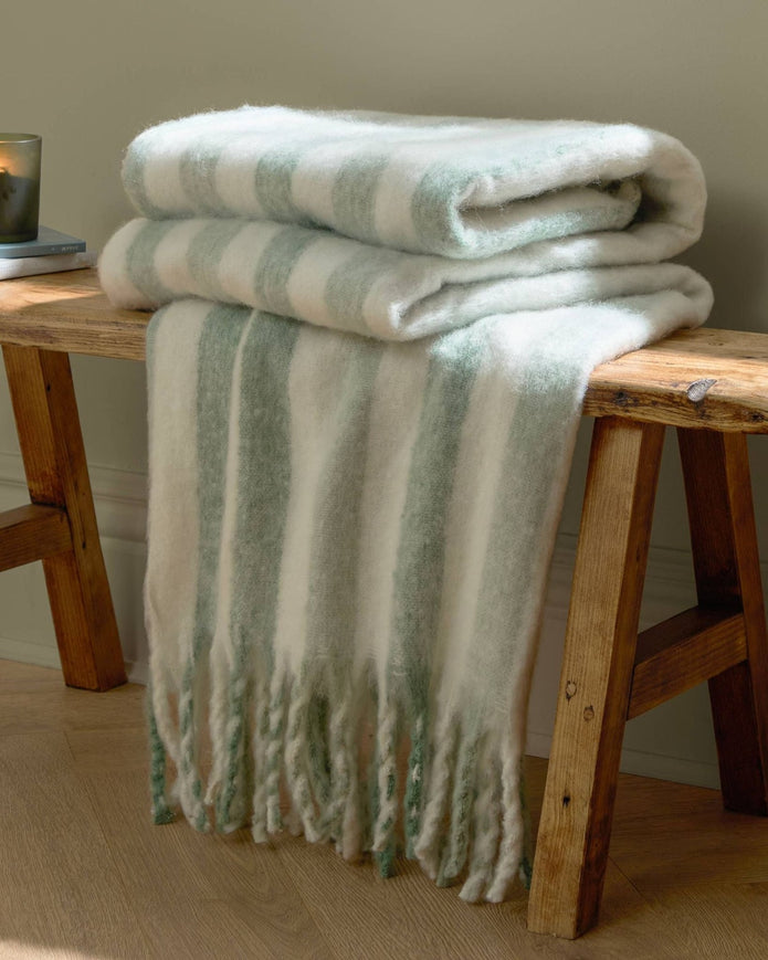 Beechwood woven stripe throw blanket in sage green from Riva Home, showcasing soft, cozy woven fabric with stripe pattern.