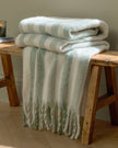 Beechwood woven stripe throw blanket in sage green from Riva Home, showcasing soft, cozy woven fabric with stripe pattern.
