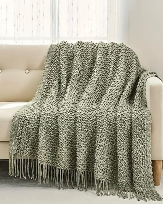Riva Home sage green lightweight throw blanket made of soft furnishings fabric, draped over a cozy armchair.