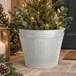 Rustic aged zinc planter pot with fine vertical ribbing and black loop handles filled with evergreen Christmas foliage