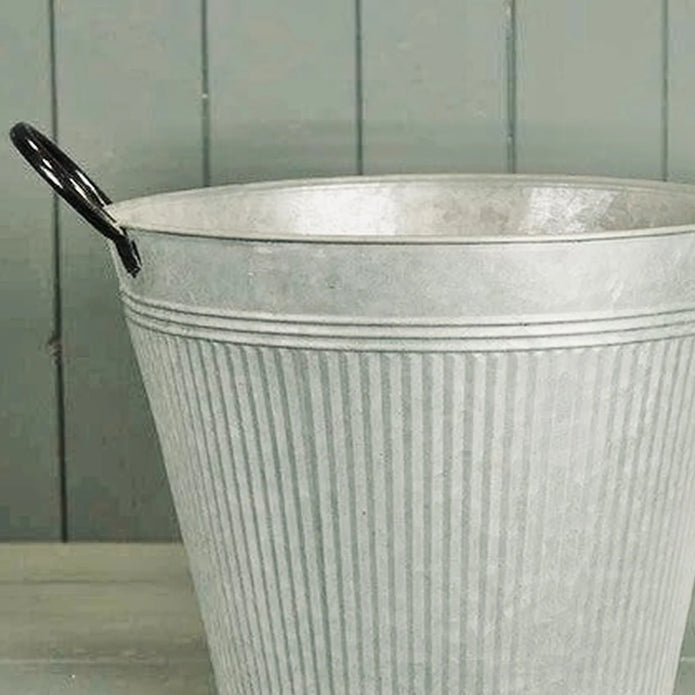Close-up detail of aged zinc planter upper rim black handle and vertical ribbed metal finish