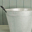Close-up detail of aged zinc planter upper rim black handle and vertical ribbed metal finish