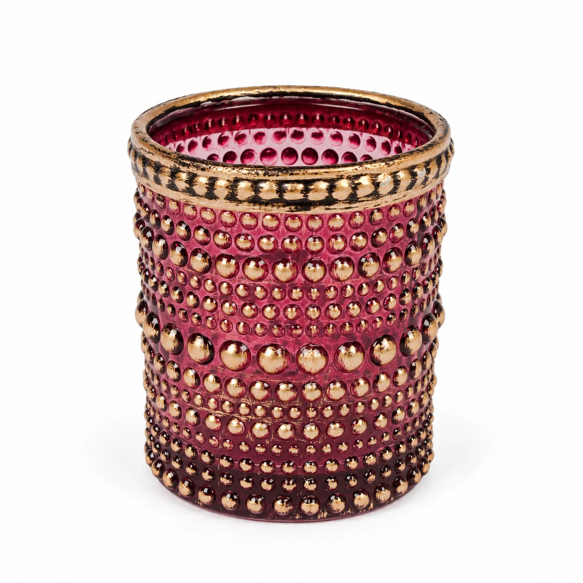 Empty burgundy dotted glass tealight holder with gold rim on white.