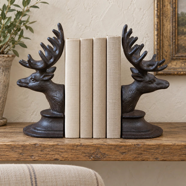 Pair of rust metal reindeer book ends holding neutral books on an oak shelf in a cream country room.
