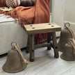 Rustic Brass Coloured Bell, large rustic bells beside a wooden stool and orange throw