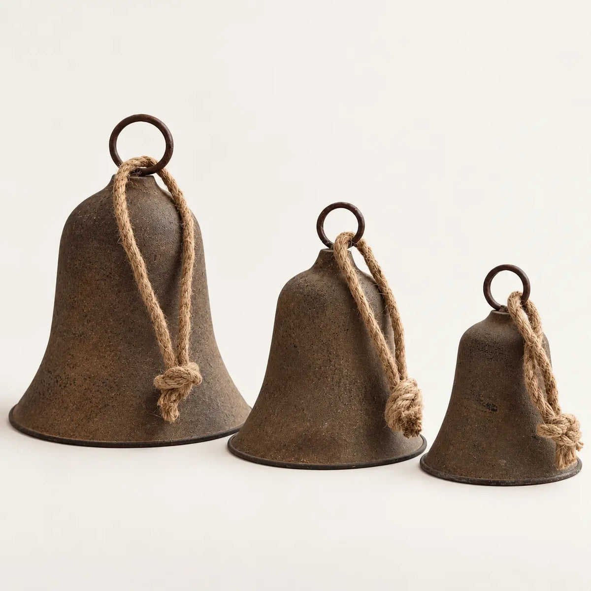 Rustic brass-coloured bell size range with small medium and large bells on a white studio background