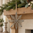 Rustic metal snowflake decoration suspended from a Christmas mantel garland.