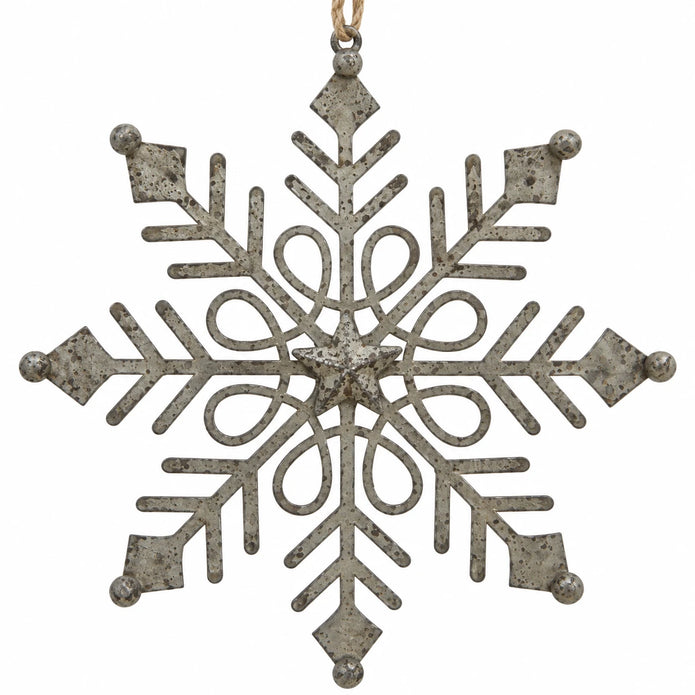 Close-up of distressed metal snowflake with central star and decorative openwork on white.