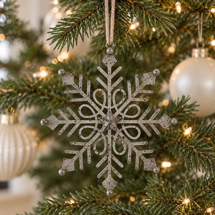 Rustic metal gem snowflake decoration hanging on a Christmas tree with neutral baubles.