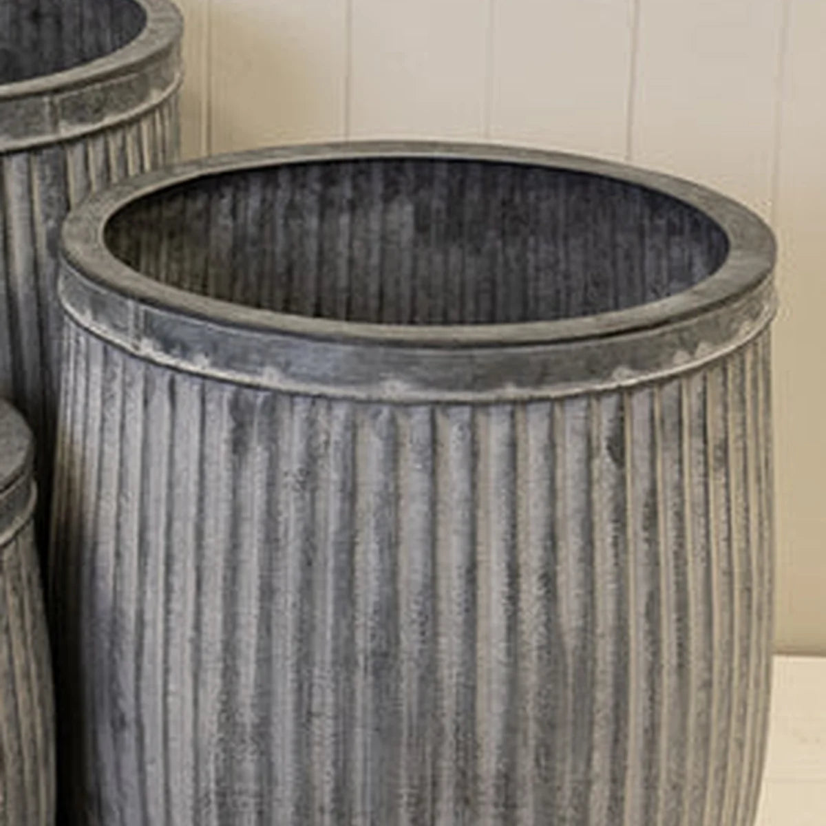Close-up of the rim and vertical fluted aged-grey metal finish of a round tub planter